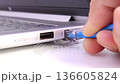 hand plugging blue lan cable into laptop ethernet port for wired network connection 136605824