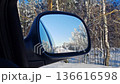 Snowy scenery reflected in car side mirror, illustrating a tranquil winter journey. View of the winter landscape from the car's side mirror 136616598