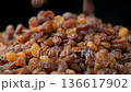 Brown raisins poured slow motion, macro food background. 136617902