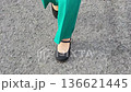 一名女子走在路上，露出雙腳，穿著綠色褲子，圖片。 136621445