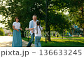 Family walk outdoors, father twirling daughter in park. Child runs toward parents, hugging mom and dad in park. Family, child, parents walk in park. Weekend in nature park in summer. People outdoors 136633245