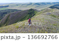 A middle-aged male tourist with a large backpack walks along a hilly ridge enjoying the fresh air and beautiful views. Real time 4k aerial video. 136692766