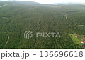 Aerial Drone View Of Dense Forest Showing Winding Stream, Distant Hills And Small Village On Fringe Tranquil 136696618