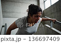 Exhausted woman escaping and climbing stairs in fear 136697409