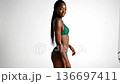 Black fashion model posing in green bikini on white background 136697411