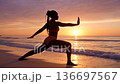 Silhouette of an african woman practicing yoga on the beach at sunset 136697567