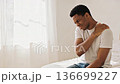 Man grimacing from severe shoulder pain. Self-massage in bedroom and expression of agony. 136699227