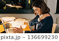 Physical discomfort due to long working hours. A woman continues working on a PC while massaging her shoulders at her desk. 136699230