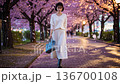 A woman walking along a cherry tree-lined avenue 136700108
