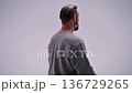 man seated against circular backdrop, minimalist studio portrait emphasizing meditation and introspection. gray sweater, clean orb lighting, profile and threequarter angles 136729265