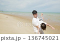 Happy family man, child, kid on summer beach travel vacation trip, playing, holding child upside down near ocean water, creating joyful memories on vast sand under bright sky. 136745021
