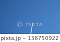 Jet aircraft flying at high altitude leaving long white contrail across clear blue sky. Vapor trail forming and stretching behind airplane during commercial flight. Aviation transport moving through 136750922