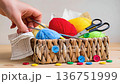 Wicker basket with colorful yarn balls and sewing tools 136751999