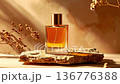 Perfume bottle on natural stone, golden glow, floral stems, soft focus texture 136776388
