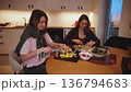 Two friends prepare a meal together in a kitchen at night 136794683