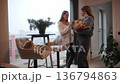 Two women play with cats in a cozy apartment on a cloudy day 136794863