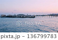 Mediterranean sea at dusk with calm water city lights and distant long pier 136799783