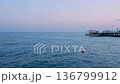 Mediterranean sea at dusk with long pier on horizon calm water and pastel sky 136799912