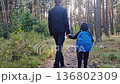 Two brothers, an older and a younger, holding hands in the park. Two young children, an older boy and a younger boy, are walking in park. children walk forward along forest road. 136802309