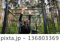Young guy, Teenager, is playing sports on a horizontal bar on an outdoor playground. Boosts strength and endurance. sports on the horizontal bar. Rear view 136803369