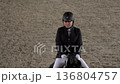 Young rider competing on horse in indoor arena tournament 4K 136804757