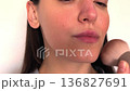 A professional makeup artist applies powder to a person's forehead using make-up brush at the saloon 136827691