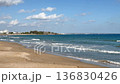Wooden boardwalk leading to a quiet sandy beach with gentle waves and a blue sea. Sunlight casts creating a serene path to the ocean. Perfect for coastal relaxation and nature-inspired travel concepts 136830426