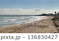 Wooden walkway extending toward the ocean, with waves and a vast blue sea under a bright sky. Minimalist coastal scene highlighting the harmony between natural beauty and human-made structures 136830427