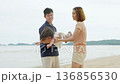 Happy family beach vacation travel, man and woman playing with child, kid enjoying summer trip, joyous moments by ocean shore, seaside holiday adventure creating lifelong memories. 136856530
