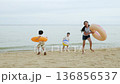 Happy family beach travel vacation, children enjoying summer trip, running near ocean waves, playing with colorful swim floats and beach ball on warm sand. 136856537