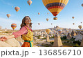 Girl traveler vacations beautiful destination in Goreme, Turkey. Fabulous Cappadocia with flying air balloons at sunrise, Anatolia 136856710