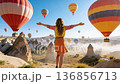 Girl traveler vacations beautiful destination in Goreme, Turkey. Fabulous Cappadocia with flying air balloons at sunrise, Anatolia 136856713
