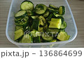 Freshly cut pickled cucumbers with herbs and garlic in a container on the table 136864699