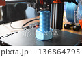 3D printer printing an object. A 3D printer printing an object from molten plastic on a work surface of 3D printer. A 3D printer creating a model. Molten plastic flowing out of an extruder close-up. 136864795