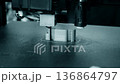 3D printer printing an object. A 3D printer printing an object from molten plastic on a work surface of 3D printer. A 3D printer creating a model. Molten plastic flowing out of an extruder close-up. 136864797