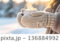 Woman in knitted mittens holding a warm cup of coffee in winter park. 136884992