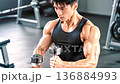 Muscular man training with dumbbells in gym. 136884993