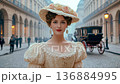Elegant young woman in vintage dress and hat walking on old European street. 136884995