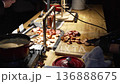 Close-up of a waiter slicing meat and sausages during a festive reception. Detailed shot of hands carving and serving freshly prepared food at a banquet table. Elegant catering moment with focus on 136888675