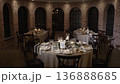 Atmospheric wedding venue setup with elegant table settings, glowing candles, and decorative lanterns creating a warm and romantic ambiance. Beautiful reception d cor prepared for guests, cozy evening 136888685