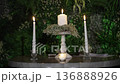 Atmospheric wedding venue setup with elegant table settings, glowing candles, and decorative lanterns creating a warm and romantic ambiance. Beautiful reception d cor prepared for guests, cozy evening 136888926