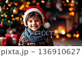 Charming little boy in a christmas hat smiles warmly, surrounded by festive decorations and glowing lights on a cold winter evening. Generative AI 136910627