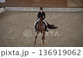 Female rider training chestnut horse in indoor arena 4K 136919062