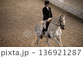 Female rider performing dressage on white horse in arena 4K 136921287
