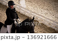 Female rider in classic uniform riding a horse in indoor arena daytime 136921666
