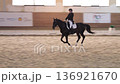 Adult woman riding a horse during dressage training in an indoor arena 136921670