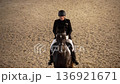 Adult female rider performing dressage in indoor arena 4K 136921671