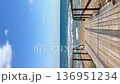 Wooden boardwalk leading to a quiet sandy beach with gentle waves and a blue sea. Sunlight casts creating a serene path to the ocean. Vertical video coastal relax and nature-inspired travel concepts 136951234