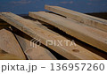 Wooden planks lie on the construction site against the background of a blue sky.  136957260