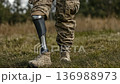 Military personnel walks confidently on grass with a prosthetic leg during a sunny afternoon outside 136988973